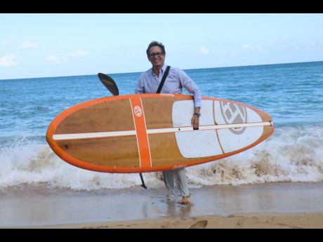 
Kyle Mais with his carbon fibre lightweight paddleboard, made from bamboo, which he uses some mornings to make his way to work. 