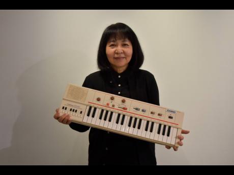 In this photo released by Casio Computer Co., Hiroko Okuda holds, at its headquarters in Tokyo, the Casio MT-40 portable keyboard player, which she created in 1981. 