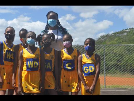 
Former Sunshine Girl Nicole Aiken-Pinnock poses with young netballers from the Jericho Primary School during the presentation of a brand new multipurpose court for the institution.