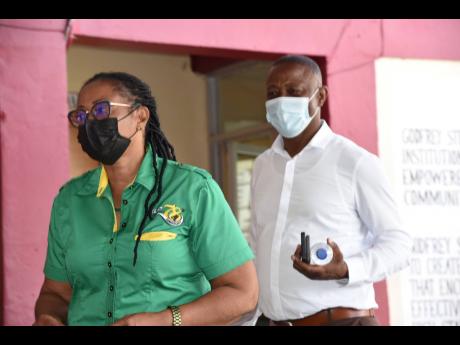 Dawnett Foster, JLP caretaker for Westmoreland Central, escorts MP George Wright out of Godfrey Stewart High School, where the Labour Party was hosting a meeting on Sunday. 