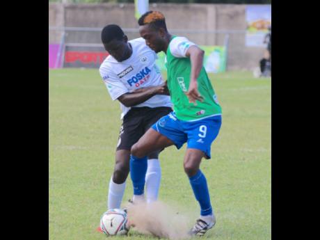 Montego Bay's Ewan Barton (right) shields the ball from a Cavalier defender during their Jamaica Premier League encounter at the Drax Hall Sports Complex on Monday.