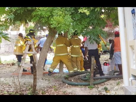 Emergency workers on the scene where landscaper Shane Lee fell to his death into a pit in Coral Gardens, St James, on Monday.
