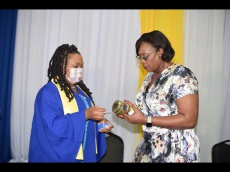Owner of Wi Jammin Caribbean Foods, Sashell Thomas (left), shows her products to Deputy Speaker of the House and Guest Speaker Juliet Holness, shortly after the graduation service of the Northwest Manchester Youth Entrepreneurship programme at the Golf Vie
