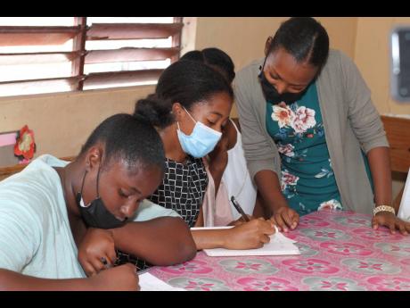 Sashana Nelson (right), a second-year medical student of Gimme-Me-Bit, Clarendon, assists sixth-form students with CAPE-level mathematics.