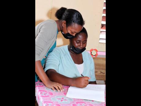 Sashana Nelson (left) assists her cousin, Veneka Nelson, with CAPE-level mathematics.