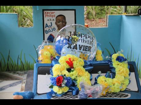 Decorations are seen at the Redlands, Clarendon, grave of Xavier Phillips, who would have celebrated his ninth birthday on Saturday. The boy was killed while watching a game of football in Howells Content, York Town, on August 8, 2021.