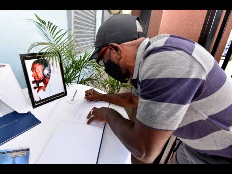 Long-time friend of the family, Courtney Waul, signs the condolence book during a private viewing of the late Winston ‘Babatunde’ Witter at Perry’s Funeral Home in Spanish Town, St Catherine, on Saturday. Witter will be laid to rest on Wednesday.