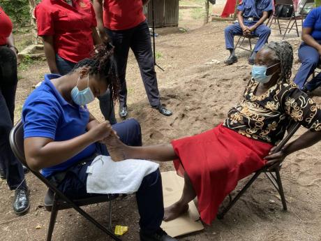 Firefighter T. Edwards from Trelawny gives senior citizen Elmena O’Conner a pedicure to mark International Women’s Day.