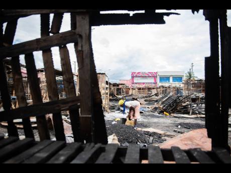 A woman is seen amid the charred wreckage of the Ray Ray Market on February 27. The market was destroyed by fire five days earlier. 