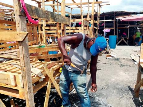 A repairman hammers away at a stall at Ray Ray Market in downtown Kingston. The market was razed in February. 