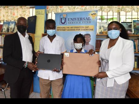 Daniel Dawes (left), CEO of the Universal Service Fund (USF), and Shanique Cornwall, human resource and administration manager, present new laptops to Delano Tucker and his sister, Deneisha Tucker, during a presentation ceremony at Guy’s Hill High School