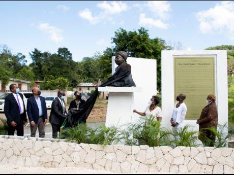Minister of Culture, Gender, Entertainment and Sport Olivia Grange is assisted by Mayor of Falmouth Colin Gager in the unveiling of a monument to supercentenarian Violet Moss Brown in Duanvale, Trelawny, on March 10. Looking on are (from left), Councillor 