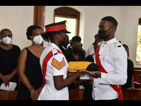Police personnel prepare to place the national flag beside the urn bearing the remains of Dr Paul Robertson during a thanksgiving service at the University Chapel in Mona on Saturday. Robertson died on February 19 aged 75. 