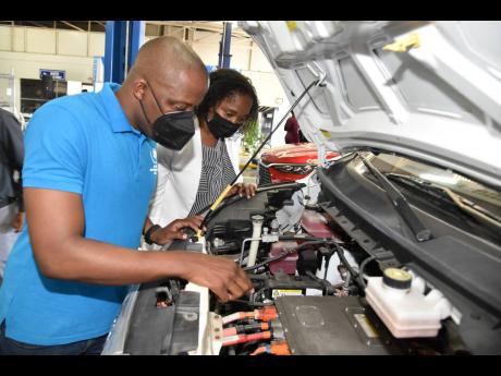 HEART/NSTA Trust and Jamaica-German Automotive School (JAGAS) trainee, James Porteous, and Tanesha Chambers Taylor, manager, HEART/NSTA Trust and JAGAS, look inside the bonnet of one of the electric vehicles that were on show during the presentation of the