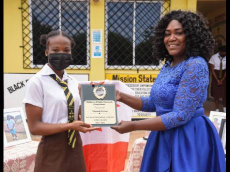 Yhannai Ferron, a sixth-form student of Black River High School in St Elizabeth, accepts an award from Sonya Moulton, founder and director of Children of Light outreach ministry for her outstanding academic achievements in a brief ceremony on Thursday, Mar