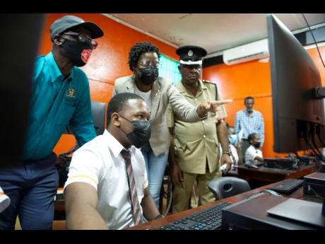 From left: Kingston Western Member of Parliament Desmond McKenzie; Melissa Taylor, director of public procurement at the Universal Service Fund; and Senior Superintendent Michael Phipps of the Kingston Western Police Division look on as a student connects 
