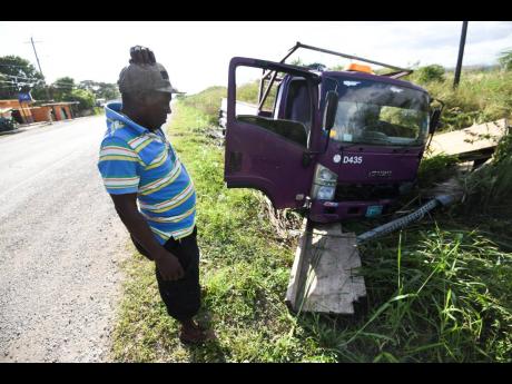 The driver of this Isuzu truck observes the mangled wreck after the vehicle ended up in a trench along the Old Harbour main road on Sunday. The driver did not appear to sustain any injuries. Jamaica registered more than 480 crash fatalities in 2021.
