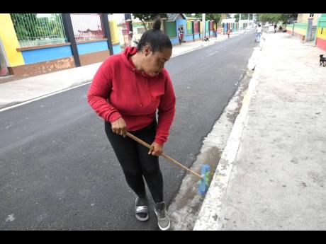 Donnette Dowe, manager of Trench Town Cultural Yard, sweeps the side of the street in proximity to the attraction in St Andrew yesterday in preparation for today’s royal visit. Dowe is hoping that publicity from today’s visit will lead to a boost in bu