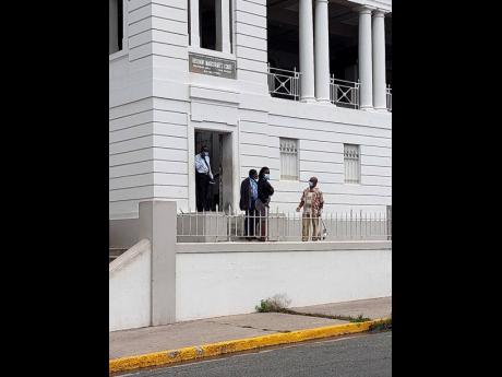Bomb experts and a policeman interact with a court worker after they inspected the Sutton Street courthouse in Kingston following a bomb threat on Tuesday.
