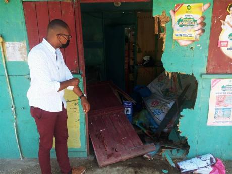 Westmoreland Western Member of Parliament Moreland Wilson viewing the blood-covered scene at the lottery outlet where the victims crashed after being shot while aboard a motorcycle in Negril. 
