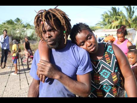 Owen Tomlinson supports his spouse, Micey Walters, after she returned from the Lionel Town Hospital, where she had gone for medical attention following the deaths of two of their three children in a fire at their home in Haylesfield, Clarendon, on Thursday