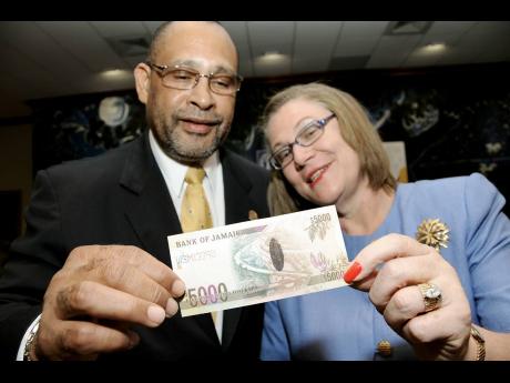 In this 2009 Gleaner file photo, Derick Latibeaudiere, then governor of the Bank of Jamaica (BOJ), examines the new $5,000 note with Professor Denise Eldemire-Shearer, widow of Hugh Shearer, after the note was presented during a launch at the BOJ.