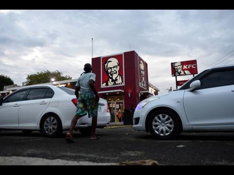 A man walks towards the KFC Cross Roads location in St Andrew on Sunday. Many fast-food restaurants and service stations have been slow to revive round-the-clock operations after the lifting of the DRMA orders.