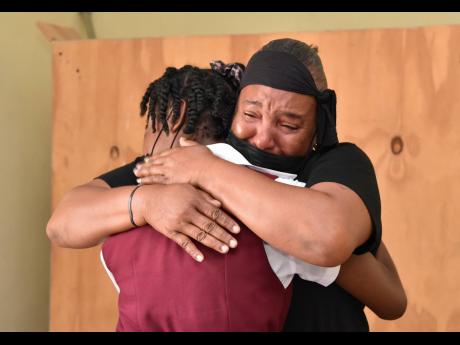 Morena Taylor, mother of 13-year-old Omarion Haniford from Crofts Hill, Clarendon, is comforted by a student from Kellits High School Monday. Omarion was stabbed fatally a day earlier. 