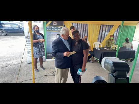  Labour and Social Security Minister Karl Samuda hands a cheque to Safiya Hamilton.