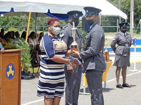 Recruit Branson Cleghorn collects the Sagicor trophy for best leadership qualities from Shauna Trowers at the Carl Rattray College in Runaway Bay, St Ann, on Wednesday. At centre is Staff Officer Christopher Brown. 