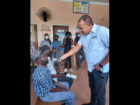 Minister of Health and Wellness Dr Christopher Tufton (right), engaging men at the Men’s Health Clinic at the Mile Gully Health Centre on Wednesday.