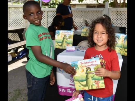 Eight-year-old author Liam Cousins (left), from Vaz Prep, gives four-year-old Ezra Chang a copy of his book during a launch at Devon House in Kingston on Saturday.