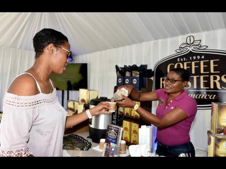 Ashlee Howe (right), marketing manager, Coffee Roasters Ltd, pours a sample of cold coffee for Sheryll Thomas during the Blue Mountain Coffe Festival held at Devon House on Saturday.