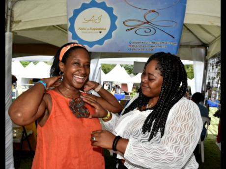 Andrea Wray smiles after trying on a piece of handmade jewellery, while being assisted by Mellisha Coke, owner of Aisha’s Inspirations, during the Blue Mountain Coffee festival held at Devon House on Saturday.