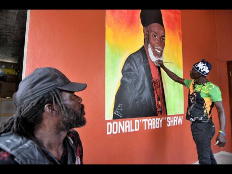 Artist Michael Robinson paints a mural in honour of Donald Orlando Shaw, better known as ‘Tabby Diamond’, at the late reggae singer’s McKinley Crescent home in St Andrew on Wednesday.