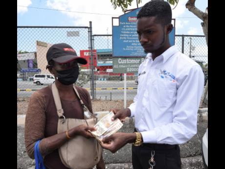 Jahzeal Clarke presents Althea Brown with cash to help with the preparation of the burial of her son who was murdered weeks ago in Kingston.