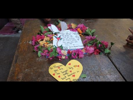 Notes and flowers left on the desk of eight-year-old Thomas James Jr yesterday as his classmates and wider Race Course Primary and Infant School community in Clarendon grieved his death. Young James was shot on Wednesday night.