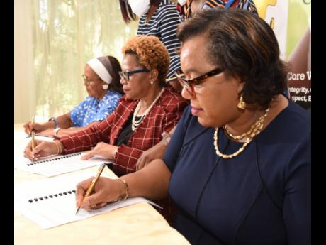 From left: Betty Ann Blaine, founder, Hear The Children’s Cry; Maureen Dwyer, permanent secretary in the Ministry of Education and Youth; and Rosalee Gage-Grey , CEO of the Child Protection Protection and Family Services Agency put ink to paper during th