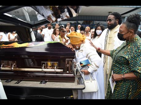 In an earlier address to the family, Entertainment Minister Olivia ‘Babsy’ Grange called herself the second mom for the Morgan family, and here joins Gramps in comforting the matriarch as she rest her head on the coffin of her late husband, Bishop Denr