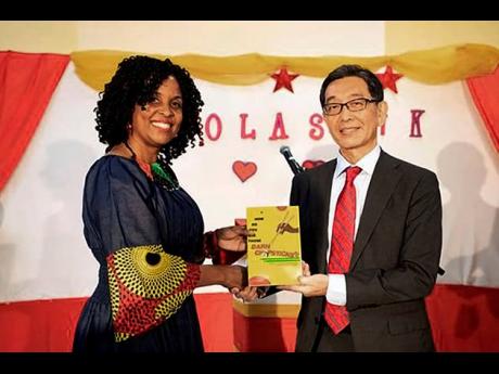 Author Tracy-Ann Hyman showcases her book at the launch alongside the Japanese ambassador to Jamaica, Masaya Fujiwara.