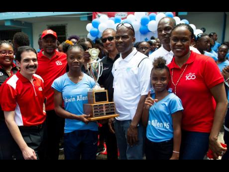 Edwin Allen High’s girls’ team captain Leona Lewis (front, second left) with the championship trophy as they celebrated their eighth straight title and ninth overall at the annual ISSA/GraceKennedy Boys and Girls’ Championships at the school yesterda