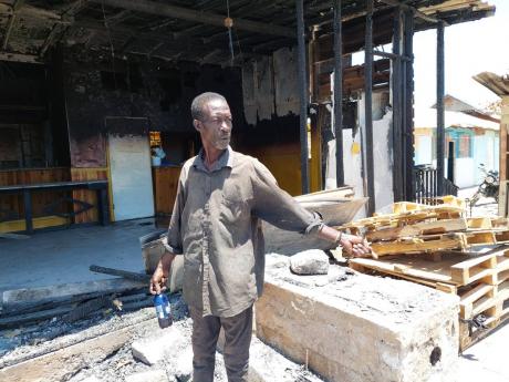 Winston Rodney stands among burnt ruins of an establishment at the New Forum Fishing Village in Portmore, St Catherine, where he used to assist in cleaning operations. To make ends meet, Rodney has had to turn to scaling fish.