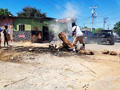 A resident mans a fiery roadblock in Denham Town in Kingston on Sunday.