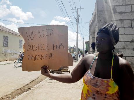 A demonstrator protests the killing of 32-year-old Horaine Glenn in Denham Town, Kingston.