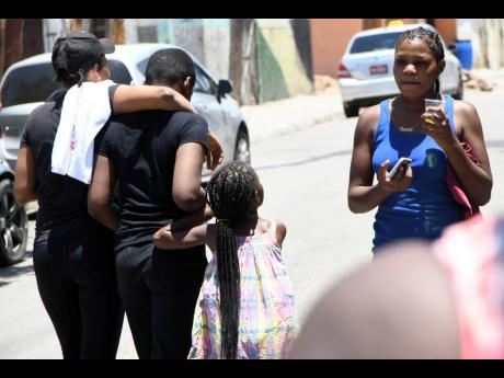 The 13-year-old son of Horaine Glenn is comforted by a family member on Monday while angry residents protest the fatal shooting of Horaine Glenn. 