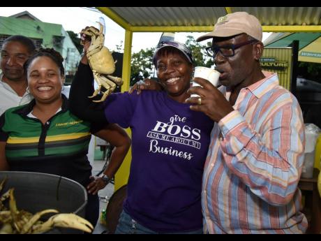 From left: Leleika-Dee Barnes, director of channel and customer marketing at J. Wray & Nephew, is all smiles as Makiesha ‘Munchie’ Walker, a vendor at Crab Circle, picks up a crab for Kingston Western Member of Parliament Desmond McKenzie as he takes a