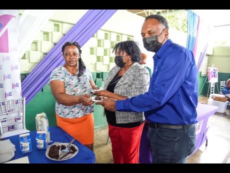 Patrina Williams (left), one of the 28 grant beneficiaries, hands a slice of cake to Mona Sue Ho, senior manager for social development at JSIF, and Omar Sweeney, managing director, JSIF.