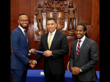 Prime Minister Andrew Holness (centre) presents the instrument of office to newly installed Youth Advisory Council of Jamaica member Jahmar Brown, as State Minister in the Ministry of Culture, Gender, Entertainment and Sport,  Alando Terrelonge, looks on.