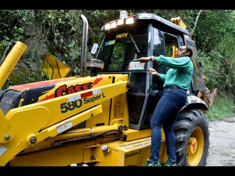 St Andrew East Rural Member of Parliament Juliet Holness talks with a tractor operator contracted to clear a blockage in Mavis Bank Wednesday. A landslide blocked access to the neighbourhood of Violet Bank, leaving residents stranded until heavy equipment 