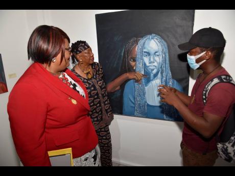 Joel Higgins (right) explains the message behind ‘Self Infliction’ to Marcia Mullings-Thompson (left), CEO at the Bellevue Hospital, and Amina Blackwood Meeks (centre). 